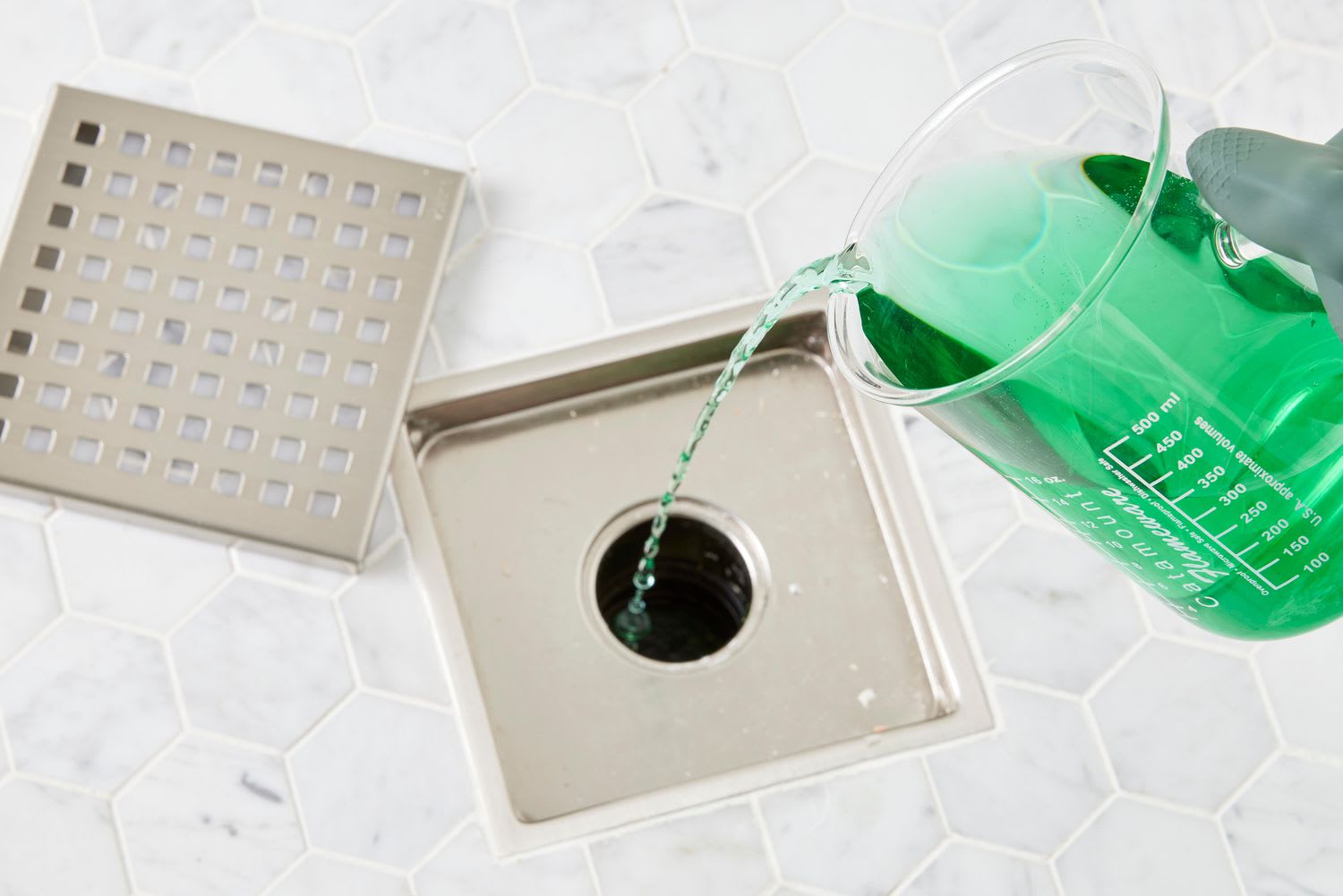green enzyme cleaner being poured into shower drain to kill drain fly larvae and remove biofilm